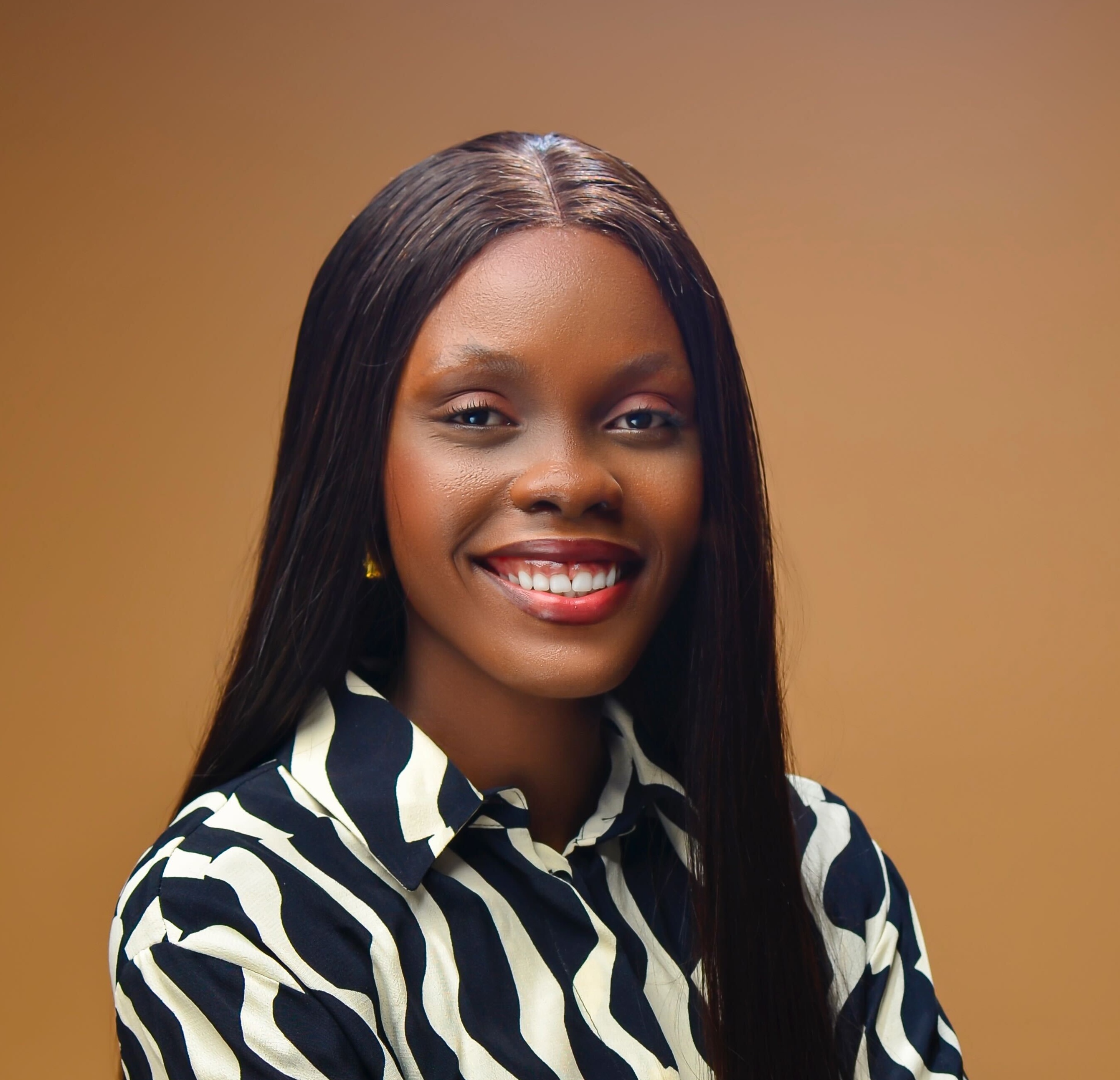 An image of Tilda Udufo wearing a black and white shirt, smiling at the camera